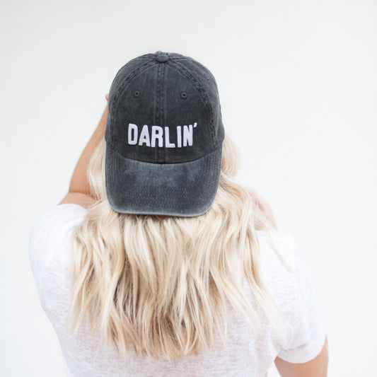 Person wearing a black cap with 'Darlin' text on a white background
